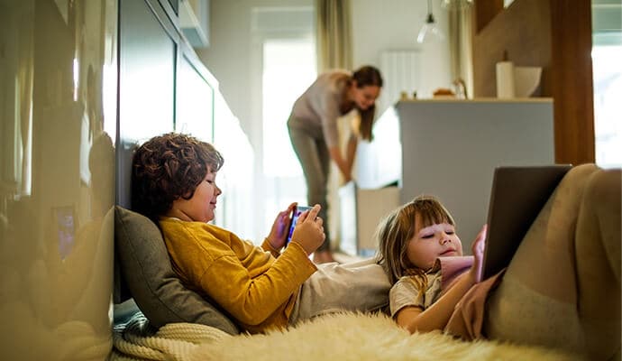 Niños usando tablets, la madre en el fondo