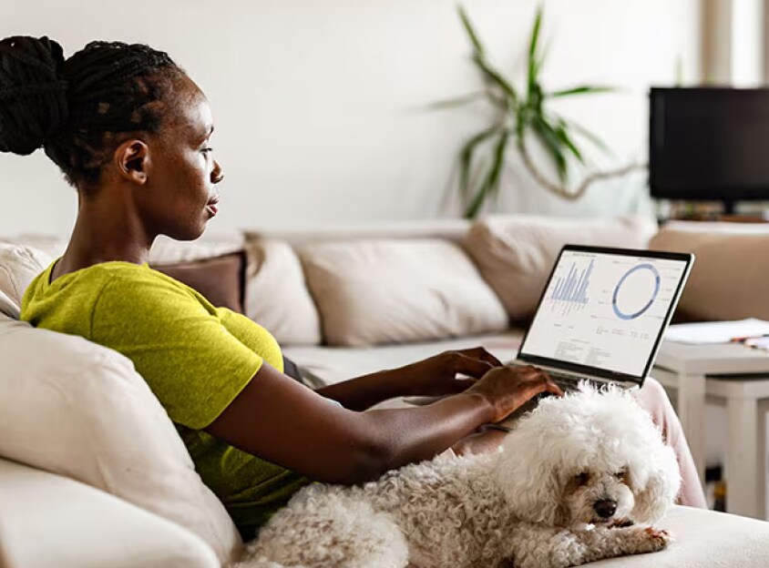 Mujer sentada con perro trabajando en una computadora portátil