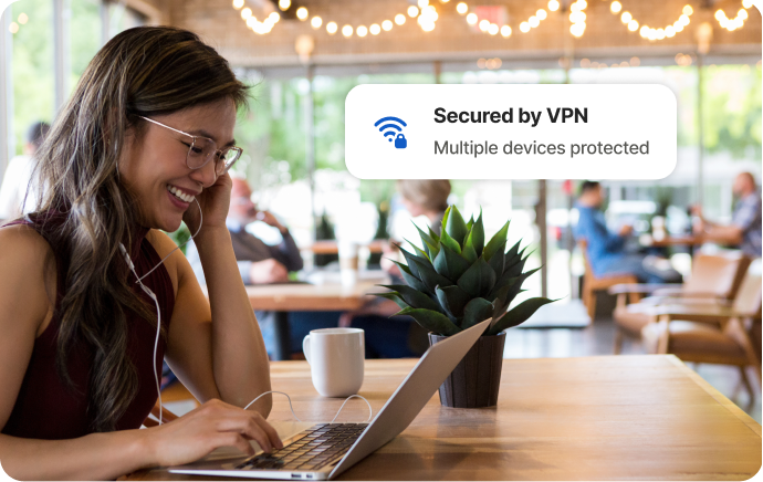 Mujer en una cafetería se ríe frente a la pantalla de un portátil